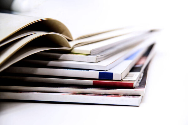 Close up of a stack of magazines on white background, shallow depth of field