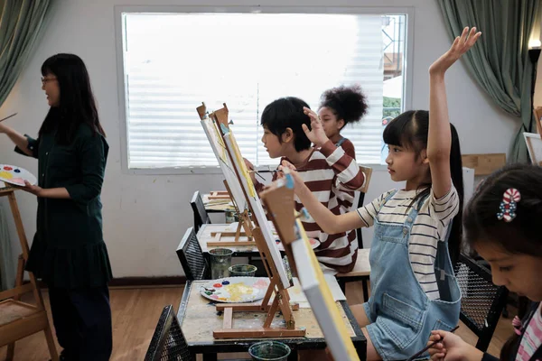 Azjatka Podnosi Rękę Aby Odpowiedzieć Pytania Nauczyciela Pracowni Artystycznej Uczniami — Zdjęcie stockowe