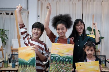 Sınıftaki bir grup sanat adamı, bir öğretmen ve öğrenci resim sergilemekten gurur duyuyor, tuval üzerinde akrilik renkli bir resim, ilkokul eğitiminde yeteneklere sahip yaratıcı öğrenme. 