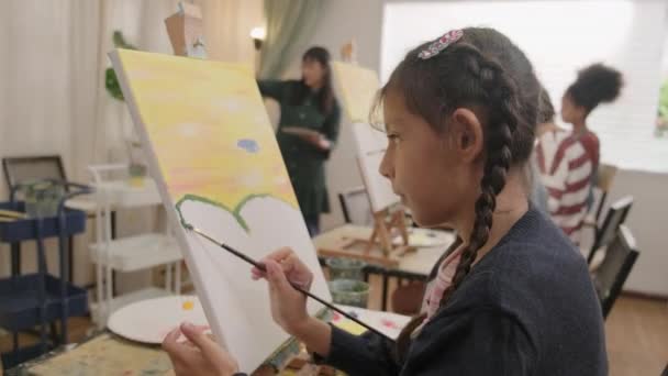 一个小女孩在艺术教室里和多种族的孩子一起 专心致志地在画布上画丙烯酸彩绘 在小学演播室里学习有才华和技巧的创造性学习 — 图库视频影像