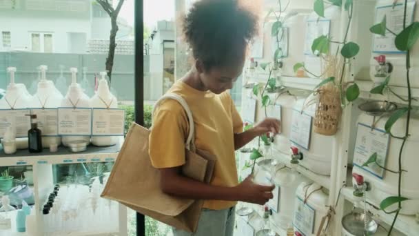 Чорна Жінка Клієнтка Наповнює Рідке Мило Пляшці Багаторазових Контейнерів Магазині — стокове відео