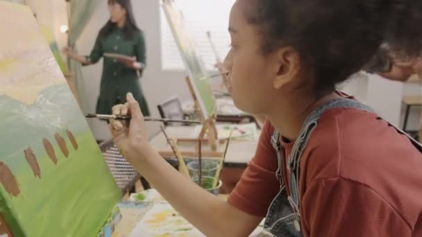 黒の女の子は 芸術教室で多人種の子供たちとキャンバス上のアクリル色の絵付け 小学校のスタジオ教育の才能とスキルを持つ創造的な学習に焦点を当てています — ストック動画