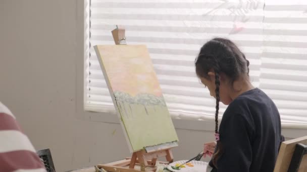 1人の少女は 芸術教室で多人種の子供たちとキャンバスにアクリル色の絵を描くことに集中し 小学校のスタジオ教育で才能とスキルを持つ創造的な学習 — ストック動画