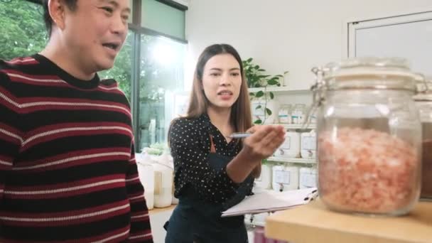 Negoziante Donna Descrive Prodotti Biologici Naturali Clienti Asiatici Maschi Negozio — Video Stock