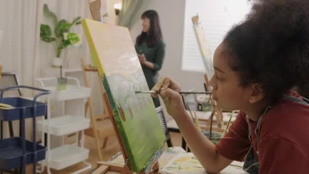 黒の女の子は 芸術教室で多人種の子供たちとキャンバス上のアクリル色の絵付け 小学校のスタジオ教育の才能とスキルを持つ創造的な学習に焦点を当てています — ストック動画