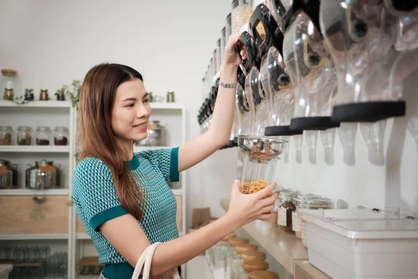 一位白种人女性顾客将谷物食品装入玻璃瓶中 将可重复使用的容器 零废物 无塑料食品 可持续的生活方式作为杠杆 免版税图库图片