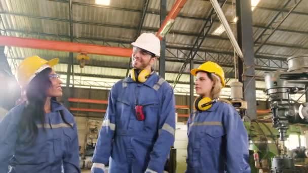 プロの工業労働者のチームは仕事の後を祝う 白人男性の生産技術者と女性の同僚はリラックスし 製造工場の機械の近くに金属製のレンチで手を上げます — ストック動画