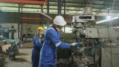Aşırı çalışan erkek endüstriyel mühendis bitkin ve baygın, iş arkadaşı imalat fabrikasında ilk yardıma yardım ediyor. Güvenlik üniformaları ve miğferler makinelerden metal kazalarından koruyabilir..