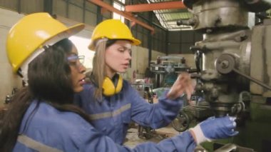 Koruyucu ve güvenlik üniformaları ve şapka giyen bir endüstri işçileri ekibi, erkek yönetici ve bayan meslektaşlar fabrikada metal fabrikalarında çalışıyor. Profesyonel üretim mühendisi.
