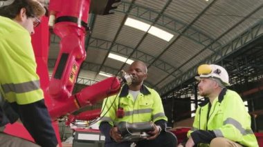 Erkek üretim mühendisleri ekibi mekanik üretim fabrikasında robotik kol, endüstriyel sektörde akıllı otomatik makineler ve gelecekteki teknolojik yenilikleri tartışıyor, test ediyor ve kontrol ediyor..