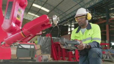 Bir Afrikalı Amerikalı üretim mühendisi test ve kontrol robot kolu mekanik imalat fabrikasında, endüstriyel sektörde akıllı otomatik makineler, ve gelecekteki teknoloji yeniliği.
