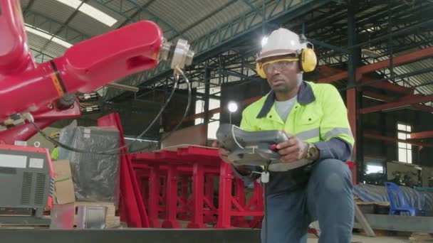 機械製造工場におけるアフリカ系アメリカ人の生産技術者のテストと制御ロボットアーム 産業ビジネスにおけるインテリジェントな自動機械 および将来の技術革新 — ストック動画