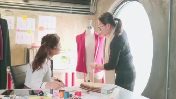 アジアの中年女性ファッションデザイナーは 若い十代の若者たちに ドレスのデザインコレクション プロのブティックの小さなビジネスのための測定テープや縫製生地で形状やサイズについての調整を教えています — ストック動画