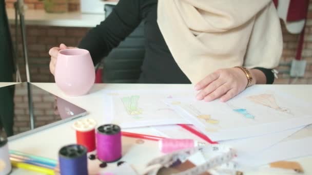 女性时装设计师手的特写镜头 放咖啡杯 在纸上画铅笔草图 拍摄服装设计系列 专业精品服装裁缝师和创意造型师 — 图库视频影像