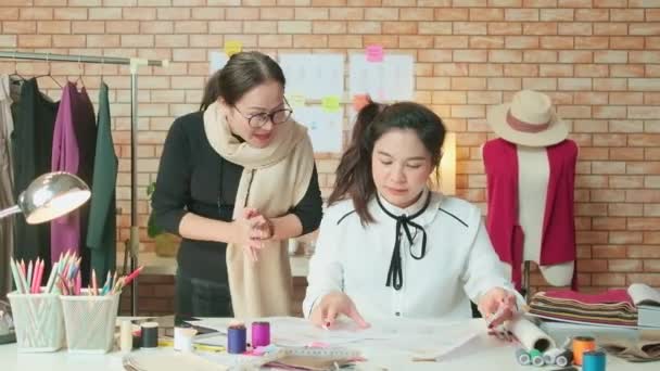 亚洲中年女性时装设计师和年轻的实习裁缝师为服装设计工作的成功欢欣鼓舞 在工作室里抛出工作纸 快乐的服装精品店小生意 — 图库视频影像