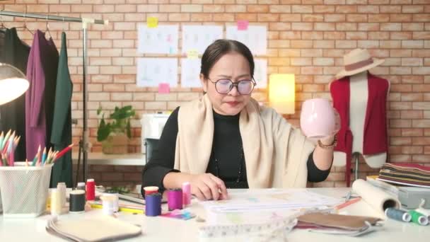 Asijský Módní Návrhářka Středního Věku Pracuje Kreativním Studiu Skicování Pití — Stock video