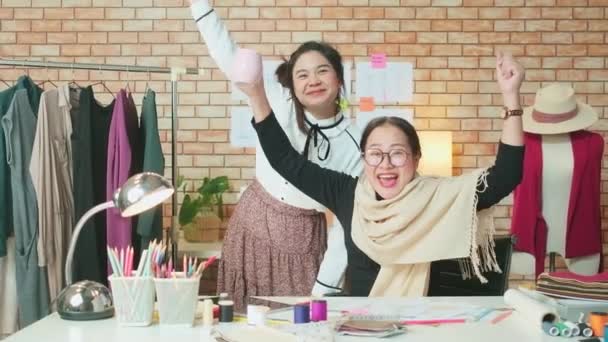 亚洲中年女性时装设计师和年轻的实习裁缝师庆祝服装设计工作的成功 并在造型师工作室满意 快乐的服装精品店小生意 — 图库视频影像