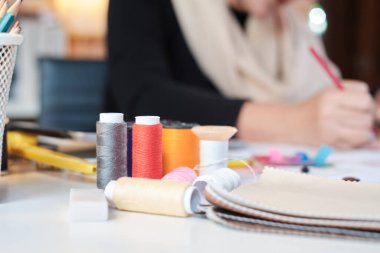 Close-up shot of colorful threads at fashion designer work in a costume studio by idea drawing sketches for fabric sewing in dress design collection, professional boutique tailor stylish occupation.