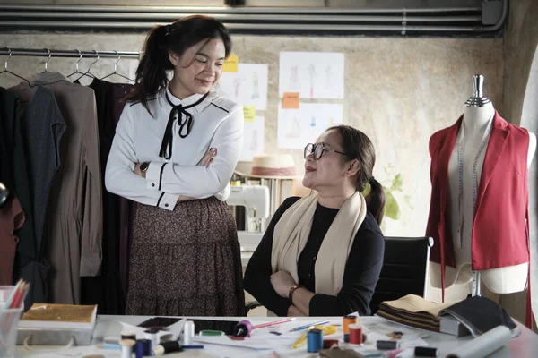 Portrait of fashion team, Asian female designer and teen assistant in studio, arms crossed, look together smile, happy sewing works for dress design, professional boutique tailor SME entrepreneur.