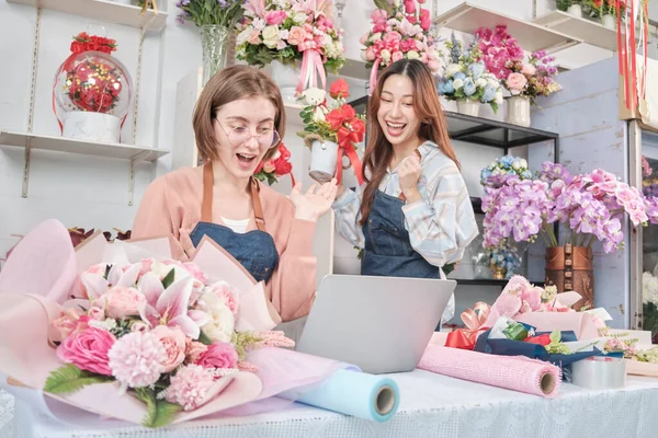 Two young beautiful women florist partners surprise with customer purchase order in e-commerce website, successful business entrepreneur, flower shop happy work, colorful flora bouquet online store.