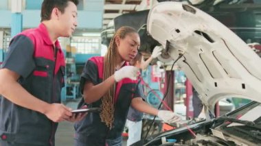 Male professional automotive supervisor advises and inspects Black female mechanic worker about liquid engine oil at car garage, service maintenance, and fixing specialist occupations auto industry.