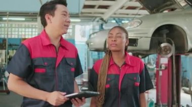 A male professional automotive supervisor and Black female inspector check repair work with female mechanic worker at car garage, service maintenance, and fix specialist occupations in auto industry.