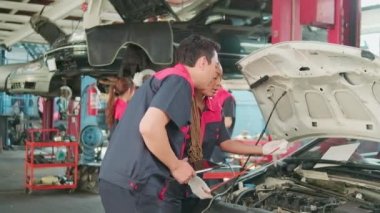 Male professional automotive supervisor advises and inspects Black female mechanic worker about liquid engine oil at car garage, service maintenance, and fixing specialist occupations auto industry.