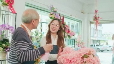 Florist workers team delivering fresh blossoms to white customer who purchased order, cashless payment by smartphone application, happy work in colorful flower shop, small business SME entrepreneur. 