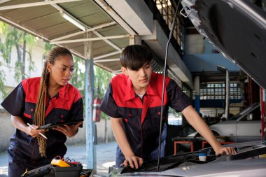Two professional automotive mechanical partners check and repair an EV car battery and hybrid engine at a maintenance garage, expert electric vehicle service, and fixing occupations auto industry.