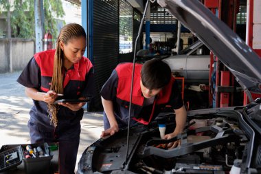 İki profesyonel otomotiv mekanik ortağı bir EV araba aküsünü ve hibrit motorunu bakım garajında, uzman elektrikli araç servisinde ve otomobil sektöründe kontrol ve onarım işlerinde kontrol ve onarım yapar..