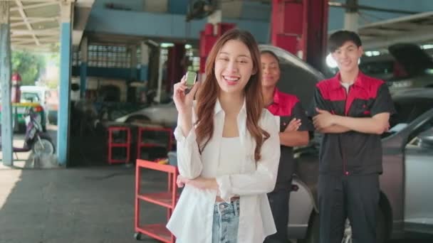 若いアジアの女性の顧客は 自動車整備士の労働者と車のキーを示しています メンテナンスガレージでの品質信頼で幸せな笑顔 プロの車両サービスセンター チェックと修理自動車業界 — ストック動画