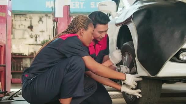 プロのアジアの男性自動車監督者は ガレージで修理のためのレンチで車のホイールナットをねじ込むために整備士を訓練しました 車両メンテナンスサービスは 業界の職業ビジネスジョブを動作します — ストック動画
