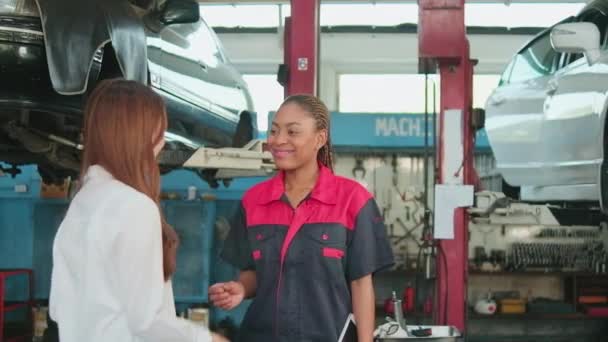 アジアの女性の顧客は メンテナンスガレージ プロの車両サービスセンター 修理チェック 修理業界での信頼と幸せな笑顔で自動車労働者と車のキーと握手を受け取ります — ストック動画