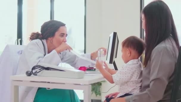 Szczęśliwy Młody Lekarz Pediatra Mundurze Drażni Małego Azjatyckiego Chłopca Zabawką — Wideo stockowe
