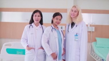 Profesyonel sağlık ekibinin portresi, üç beyaz üniformalı kadın doktor birlikte bakıyor, eğlenceli gülüyor ve gülümsüyor, hastane kliniğinde mutlu fiziksel işler yapıyor..