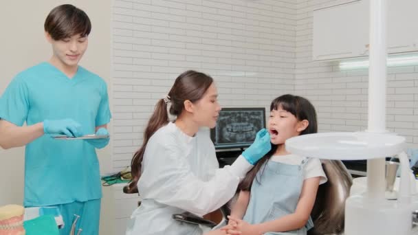 Ασιάτισσα Οδοντίατρος Και Βοηθός Παιδοδοντίατρος Ελέγχει Και Εξετάζει Δόντια Ενός — Αρχείο Βίντεο