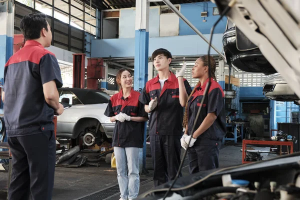 Male expert supervisor engineer train and discuss with professional mechanic worker teams, inspect repair work at car service garage, harmonious group, and do maintenance jobs in automotive industry.