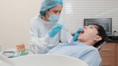 Asyalı kadın diş hekimi genç erkek dişlerini ve diş ağrısı stomatolojisini diş kliniğinde, sağlık kontrollerinde ve doktor muayenehanesinde profesyonel ortodontik sağlık hizmetlerinde inceleyecek..