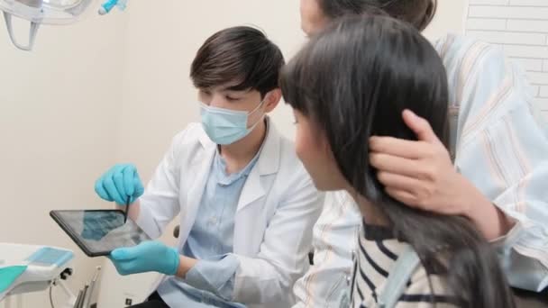 아시아 의사는 진료소에서 태블릿에서 위생을 소녀와 어머니에게 Ray 스캔을 설명합니다 — 비디오