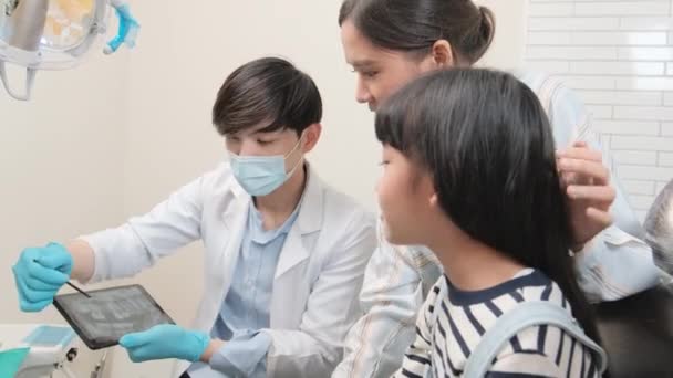 아시아 의사는 진료소에서 태블릿에서 위생을 소녀와 어머니에게 Ray 스캔을 설명합니다 — 비디오
