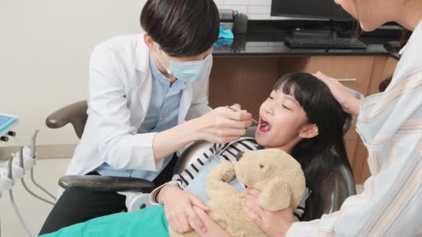 在儿童医院和家庭医院的牙科诊所 健康卫生和专业牙齿矫正保健工作中 亚洲男性牙医与母亲一起检查和检查女孩的牙齿 — 图库视频影像