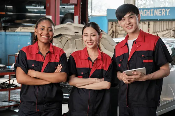 Portrait of multiracial professional mechanic team arms crossed and look at camera, work at car service garage, happy maintenance jobs, check and repair occupation in automotive industry business.