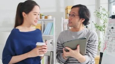 İki genç Asyalı şirket ortağı gelişigüzel küçük işletme ofisinde tartışıp fikir alışverişinde bulunuyor, pazarlama işleri, ilham ile mutlu beşlikler ve E-ticaret serbest girişimcileri.