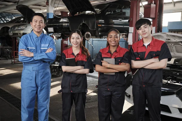 Portrait of multiracial professional mechanic team arms crossed and look at camera, work at car service garage, happy maintenance jobs, check and repair occupation in automotive industry business.