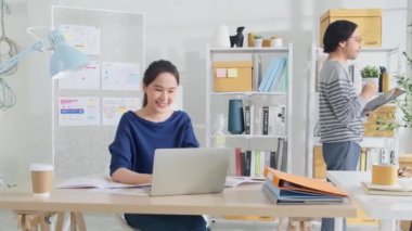 İki genç Asyalı girişimci şirket ortağı, gelişigüzel bir küçük işletme ofisinde, tablet ve dizüstü bilgisayarla çalışan online serbest ticaret girişimcileri ve iş arkadaşları olarak konsantre olup düşünürler..