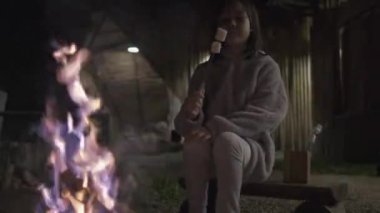 Küçük bir Asyalı kız şenlik ateşinde kızartılmış marshmallow barbeküsü kamp gezisi doğa öğrenme deneyimi, açık hava yaşam tarzı tatili ve kırsal macera gezisi..