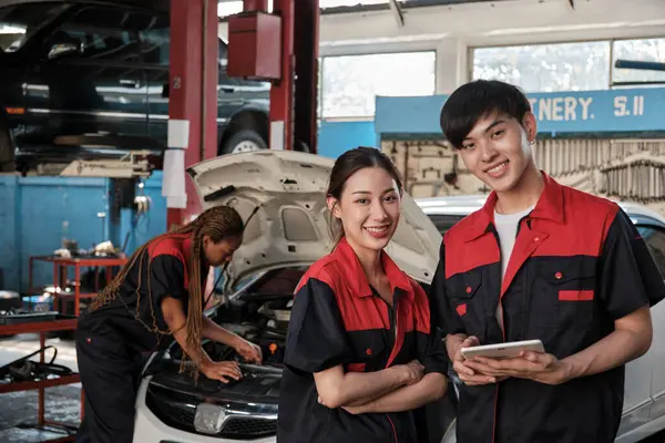 两名亚洲专业技师 男工程师和合伙人微笑着看着相机 检查修车厂的维修工作清单 维修维修汽车 以及修理专业汽车工业 图库照片