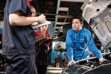 Asyalı erkek otomotiv mühendisi, otomobil bakım ve onarım çalışmalarını tamirci ekibinin tamirhanesinde ve otomobil endüstrisinde uzman işlerinde tanımladı..