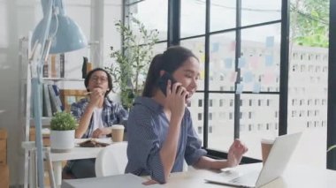 İki genç Asyalı girişim ortağı gündelik bir küçük işletme ofisinde çalışmaya, müşterilerle cep telefonuyla konuşmaya, dizüstü bilgisayarlı internet servis işleri ve E-ticaret KOBİ iş arkadaşı.
