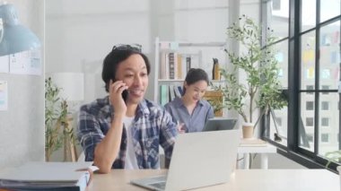 İki genç Asyalı girişim ortağı gündelik bir küçük işletme ofisinde çalışmaya, müşterilerle cep telefonuyla konuşmaya, dizüstü bilgisayarlı internet servis işleri ve E-ticaret KOBİ iş arkadaşı.